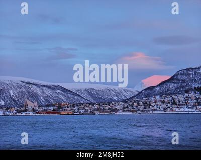 Tramonto sulla cattedrale nel paesaggio invernale del porto di Tromso in un fiordo sulla costa settentrionale della Norvegia con montagne innevate Foto Stock