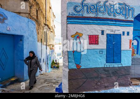 Nord Africa. Marocco. Chefchaouen. Una donna vestita di djelaba che cammina in una strada blu della medina Foto Stock