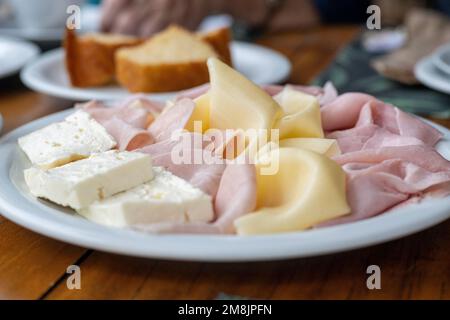 Prima colazione brasiliana con formaggio Minas (queijo minas), prosciutto e formaggio Prato (queijo Prato) servito con pane di mais, sotto la luce naturale, realista Foto Stock