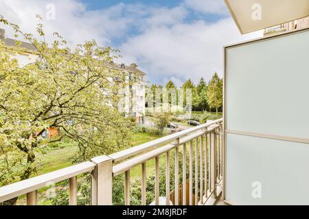 un balcone con alberi sullo sfondo e cielo blu sopra di esso, come visto da un balcone appartamento vista finestra Foto Stock