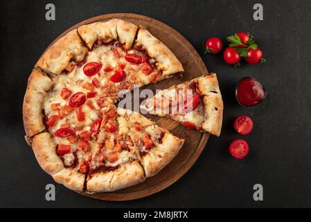 La Pizza Margherita sulla pietra nera dello sfondo. In casa Pizza Margherita con pomodoro, basilico e mozzarella. Foto Stock