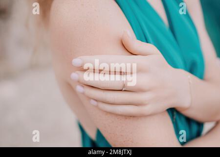 Ritratto donna rosso. Mano di giovane caucasica ricciola rossa con anello. Primo piano ritratto carina donna in un abito lungo menta Foto Stock