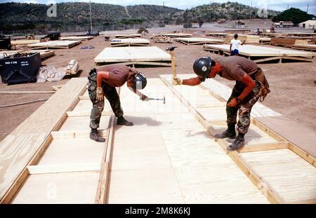 US Navy Seabees da Naval Mobile Construction Battalion 4 (NMCB-4) e carpentieri migranti cubani costruiscono strutture di tenda a sostegno duro per il villaggio Bravo a Camp Bulkeley. La costruzione è una soluzione nel tentativo di migliorare la qualità della vita dei migranti. Subject Operation/Series: SEA SIGNAL base: Guantánamo Bay Paese: Cuba (CUB) Foto Stock