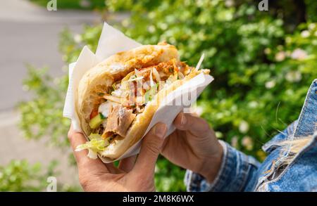 Donna in possesso di un Doner Kebab (panino) in Germania famoso kebab fast food snack in pane piatto. Foto Stock