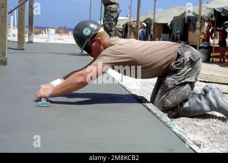 PICCOLO ufficiale 3rd Classe Blackard, Stati Uniti Navy Seabee, lavora per mettere i tocchi finali su una fondazione per una struttura bagno a Camp Foxtrot negli Stati Uniti Base navale. La costruzione migliorerà la qualità della vita dei migranti nel campo. Base: Guantánamo Bay Nazione: Cuba (CUB) Foto Stock