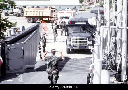 Un autobus dell'aviazione militare statunitense che trasporta immigrati cubani viaggia su un'imbarcazione da sbarco della Marina degli Stati Uniti presso la base navale di Guantanamo Bay. L'imbarcazione di atterraggio trasporterà gli immigrati attraverso la baia di Guantánamo fino alla linea di volo della base. Soggetto operativo/Serie: SEA SIGNAL base: Naval Station, Guantánamo Bay Paese: Cuba (CUB) Foto Stock