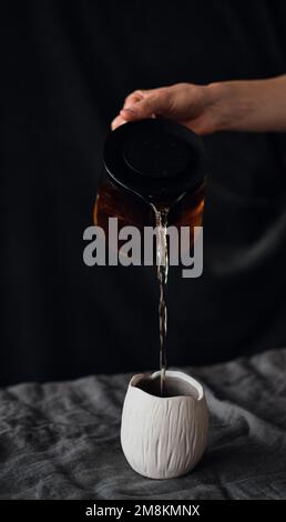 versare il tè da una teiera in una tazza di terracotta Foto Stock