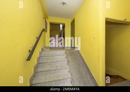 Scale di granito grigio di una casa con una rampa inutilizzabile a causa della sua ripidità e pareti gialle Foto Stock