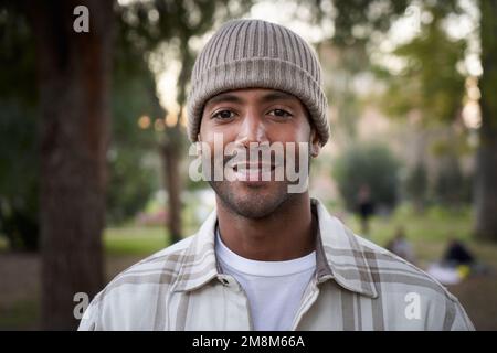 Ritratto di bel giovane africano sorridente con cappello a maglia che guarda camera espressione positiva Foto Stock