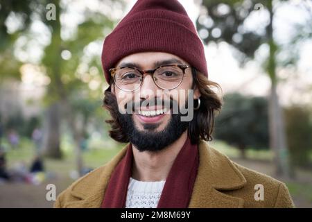 Ritratto bel giovane uomo caucasico sorridente con cappello invernale guardando fotocamera espressione positiva Foto Stock