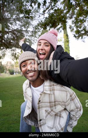 Verticale Ritratto di felice giovane coppia multietnica che prende un selfie. Bella ragazza che si diverte Foto Stock