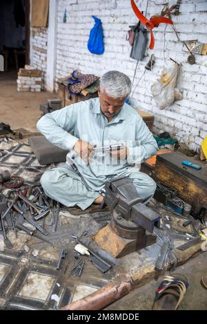 Un fabbro che lavora su un revolver in una fabbrica di armi, Peshawar, Pakistan Foto Stock