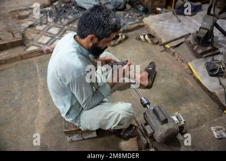 Un fabbro che lavora su un revolver in una fabbrica di armi, Peshawar, Pakistan Foto Stock