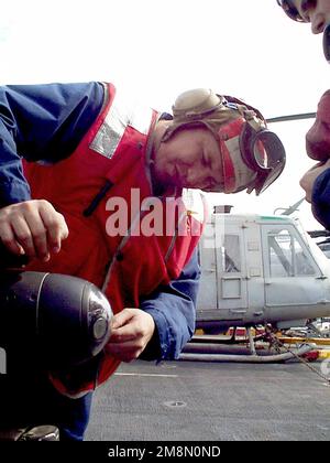 US Marine Corps GUNNERY Sergeant (GYSGT) Thomas M. Martinez pulisce l'obiettivo su un missile aria-superficie AGM-114 Hellfire, a corto raggio, guidato da laser, montato su un elicottero AH-1 Sea Cobra Attack. A bordo della nave d'assalto anfibio USS GUAM (LPH 9) attualmente nel Golfo Persico, come parte di una maggiore presenza militare per applicare le sanzioni ONU contro l'Iraq. Operazione SOUTHERN WATCH, 21 febbraio 1998. Funzionamento/Serie del soggetto: BASE OROLOGIO SOUTHERN: USS Guam (LPH 9) Foto Stock