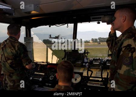 Technical SGT(TSgt) Joe Odom(right), Air Traffic Controller dello Squadron di supporto operativo 46th, Eglin AFB, Florida, aiuta a coordinare il traffico aereo a Tirana, Albania, 31 maggio 1999. I controllori del traffico aereo delle forze aeree e dell'esercito coordinano tutto il traffico aereo militare presso l'IAP di Tirana a sostegno dell'operazione Shining Hope e della Task Force Hawk. Un elicottero di attacco AH-1 dell'esercito degli Stati Uniti è visto sullo sfondo volare basso sopra la pista da sinistra a destra. Soggetto operativo/Serie: BASE DI SPERANZA SPLENDENTE: Tirana Paese: Albania (ALB) Foto Stock