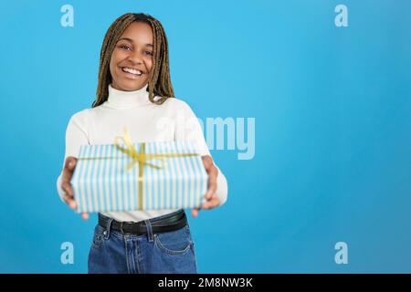 Donna africana sorridente alla macchina fotografica mentre dà un regalo Foto Stock