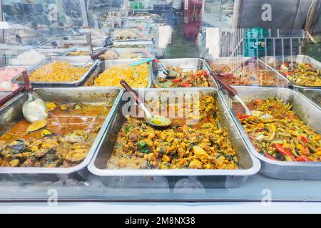 Una tipica esposizione di cibo per le strade del centro di Bangkok, pronto per servire, in piatti di acciaio. Verdure speziate, maiale, ceci, peperoncini, melanzane Foto Stock