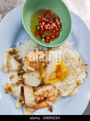 Street food di gamberi e calamari di carne, un piatto tipico per le strade della Thailandia, molto economici, servito con salsa di pesce e peperoncino fresco caldo. Foto Stock