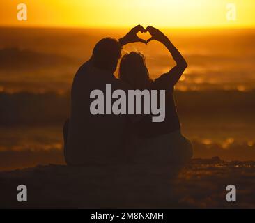 Dorso di una coppia che forma un cuore con le mani. Amare la coppia matura facendo un gesto con le mani. Coppia sposata affettuosa sul Foto Stock