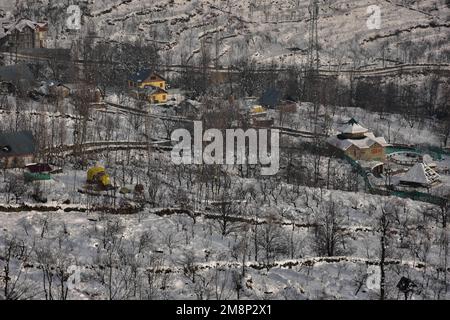 Srinagar, India. 14th Jan, 2023. Una vista generale delle case coperte di neve e dei campi dopo una fresca nevicata alla periferia di Srinagar. Il tempo è migliorato nella valle del Kashmir dopo giorni di nevicate e piogge da moderate a pesanti. Nel frattempo, gli valanghe sono stati segnalati il sabato nel distretto di Bandipora e nella stazione di Sonamerg Hill che hanno assistito a nevicate da moderate a pesanti negli ultimi giorni. Questo è il secondo incidente riportato nella popolare stazione collinare negli ultimi due giorni. Due operai sono morti giovedì quando una valanga ha colpito il sito di lavoro di un'impresa di costruzione a Sonamerg. Credito: SOPA im Foto Stock