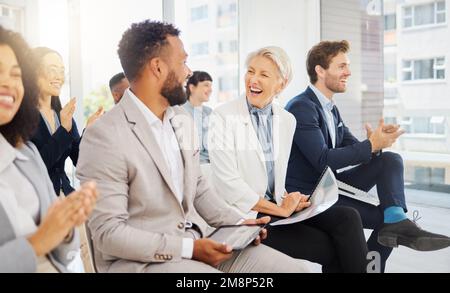 Allegra donna d'affari caucasica matura che ride con un collega durante una presentazione in un ufficio. Donna nel pubblico sorridente mentre ascolta Foto Stock