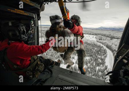 10 gennaio 2023 - Joint base Elmendorf-Richardson, Alaska, USA - Alaska Army Guard staff Sgt. Brad McKenzie, a sinistra, un capo equipaggio e un operatore di sollevamento, assiste SPC. Matthew Tucker, a destra, una medica di volo, entrambi assegnati a Golf Company, distaccamento 2, 2-211th Generale supporto Aviation Battaglione, Mentre viene issato in un elicottero Black Hawk dell'Alaska Army National Guard UH-60m con un incidente nozionale sulla base congiunta Elmendorf-Richardson, Alaska, gennaio. 10, 2023. Gli equipaggi aerei della Guardia militare hanno condotto l'inserimento aereo, l'evacuazione medica e l'addestramento delle argine con gli Airmen speciali tattici, assegnati a 24th Speciale Foto Stock