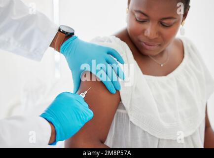 Medico che inietta un paziente nel braccio. Mano di un medico che inietta un paziente con un ago. Donna afroamericana che viene iniettata con un vaccino Foto Stock