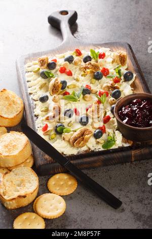 Tabellone per burro alimentare di tendenza con frutta secca, pistacchi, nocciole e mirtilli in primo piano sul tavolo. Verticale Foto Stock