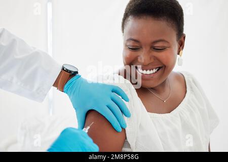 Donna afroamericana sorridente prima dell'iniezione. Paziente che viene iniettato con un vaccino. Medico che tiene un ago riempito con una cura. Donna che ottiene Foto Stock