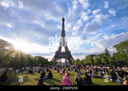Parigi, Francia - Maggio, 2022: Persone in erba, avendo un picnic a Champ de Mars con la Torre Eiffel al tramonto Foto Stock
