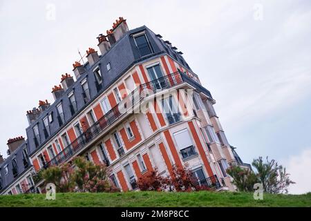 Parigi, Francia - Maggio, 2022: Un edificio parigino in mattoni del 19th ° secolo con un pendio erboso in primo piano. Foto Stock