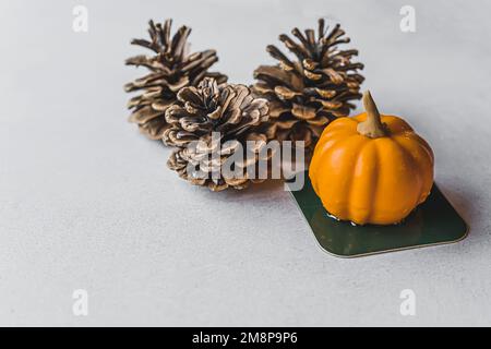 Piccolo dessert di mousse a forma di zucca arancione su un tavolo di pietra con pineconi decorativi. Dolci natalizi autunnali. Ringraziamento. Vacanze. Scatto orizzontale . Foto di alta qualità Foto Stock