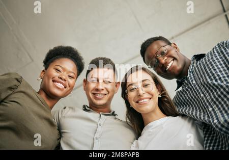 Ritratto di felice unito giovane squadra di affari abbracciandosi l'un l'altro. Diversi gruppi di razze miste di uomini e donne in fila nel loro ufficio, huddling Foto Stock