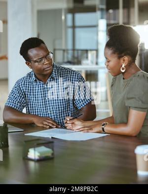 Due imprenditori afroamericani che hanno un incontro e che guardano insieme un rapporto sul lavoro. Uomo d'affari e donna d'affari prendendo appunti mentre Foto Stock