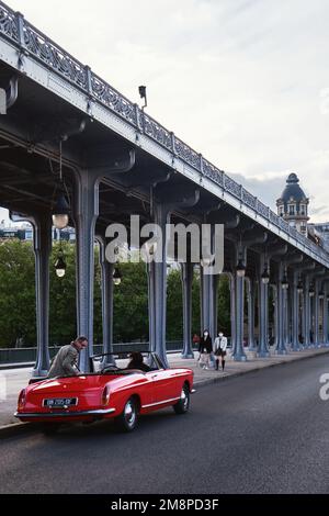 Parigi, Francia - Maggio, 2022: Un'auto sportiva rossa con lunghe colonne d'acciaio del Viadotto Passy situato al Pont de Bir Hakeim Bridge Foto Stock