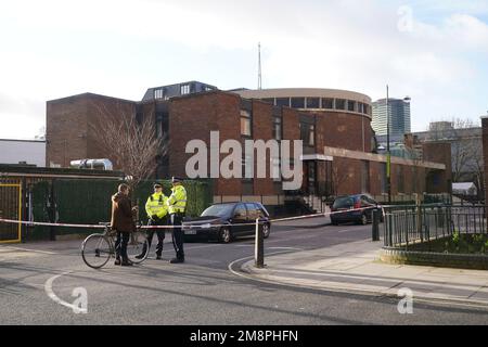 Polizia sulla scena di una sparatoria fuori di un servizio commemorativo che si teneva nella chiesa cattolica romana di San Aloysius su Phoenix Road, a Euston, alle 1,30pm circa del sabato. Una ragazza di sette anni è in una condizione di pericolo di vita a seguito del sospetto drive-by sparando fuori dalla chiesa, mentre un'altra ragazza e quattro donne sono state ferite nello stesso incidente. Data immagine: Domenica 15 gennaio 2023. Foto Stock