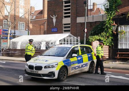 Polizia sulla scena di una sparatoria fuori di un servizio commemorativo che si teneva nella chiesa cattolica romana di San Aloysius su Phoenix Road, a Euston, alle 1,30pm circa del sabato. Una ragazza di sette anni è in una condizione di pericolo di vita a seguito del sospetto drive-by sparando fuori dalla chiesa, mentre un'altra ragazza e quattro donne sono state ferite nello stesso incidente. Data immagine: Domenica 15 gennaio 2023. Foto Stock