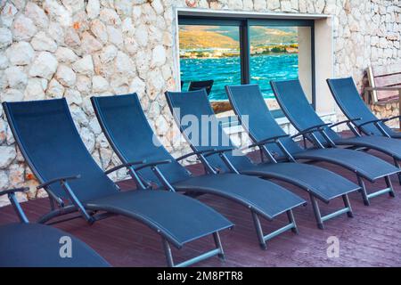 Sedie a sdraio in località turistica. Riflessione sul mare nella finestra . Sedie salotti in fila Foto Stock