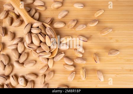 Pistacchi in Un cucchiaio di legno e Copia spazio su uno sfondo di legno, vuoto. Concetto di pistacchio nel Menu Foto Stock