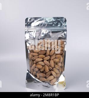 Pistacchi sbucciati in Confezione DOYPACK o plastica. Pistacchi isolati in una confezione trasparente su sfondo bianco. Foto Stock