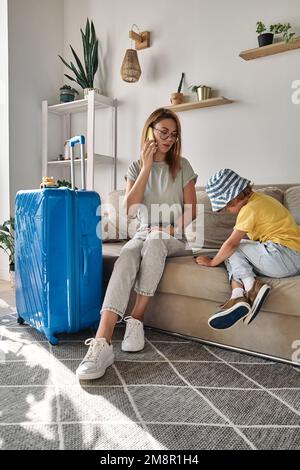 La famiglia madre e il bambino acquistano biglietti per vacanze o viaggi utilizzando il telefono cellulare e il tablet a casa Foto Stock