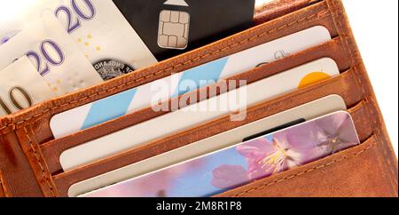 primo piano di un mucchio di banconote da dieci e venti sterline con un portafoglio in pelle marrone e una carta di credito nera Foto Stock
