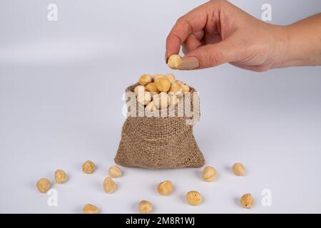 La mano della donna tiene noci o nocciola. Sacco di noci isolato su uno sfondo bianco Foto Stock