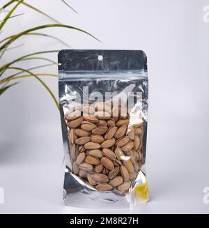 Pistacchi sbucciati in Confezione DOYPACK o plastica. Pistacchi isolati in una confezione trasparente su sfondo bianco. Foto Stock