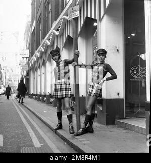 Un uomo e una donna che si posano in abiti identici di jumper e gonna nella elegante Carnaby Street, Londra 1968. Foto di Tony Henshaw Archivio Foto Stock