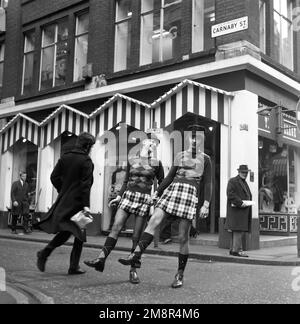 Un uomo e una donna che si posano in abiti identici di jumper e gonna nella elegante Carnaby Street, Londra 1968. Foto di Tony Henshaw Archivio Foto Stock