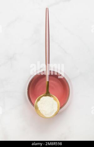 Additivi alimentari eccellenti. Proteina collagene in polvere, cucchiaio e bicchiere d'acqua. Supplemento collagene per pelle, articolazioni e budella. Foto Stock