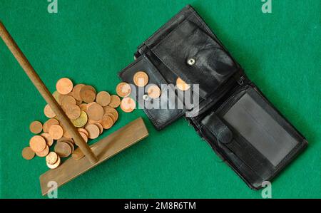 portafoglio e monete tolti con il rake della roulette, crisi finanziaria, inflazione, concetto di pericolo di povertà. Foto Stock