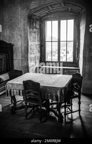 Un'immagine in scala di grigi di un vecchio stile interno soggiorno con tavolo e sedie vintage Foto Stock