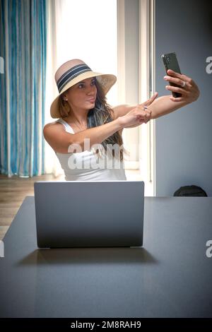 Una foto verticale di una donna in movimento che si pone e prende un selfie con il telefono Foto Stock